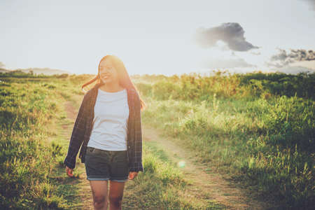 Asian woman standing at grass field with mountain and sunset sky scenic landscape background with copy space.の写真素材