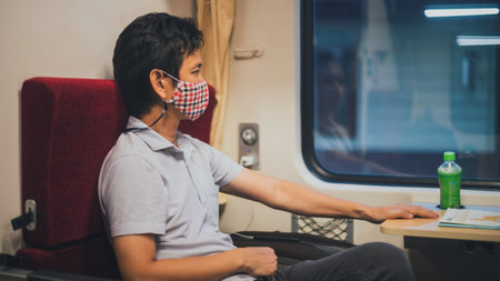 Asian man wearing face mask  sitting alone on the train.Concept of public transportation Carefully...