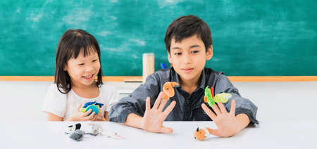 Asian happy school girl and boy learning and play with toy model on black board background with copy...