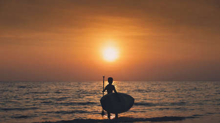 Silhouette of young man playing paddle board in sea with the sunset sky background.Water sports concept And travel in the summer.の写真素材