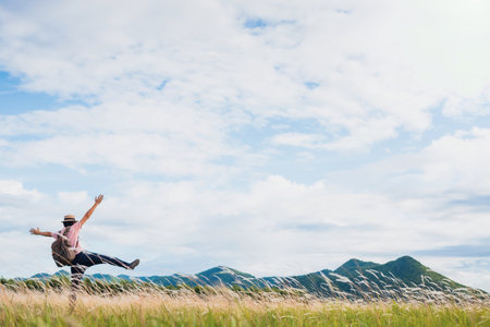 Asian man walking and take photo in meadow flower field landscape background.Concept of travel in summer season at Thailand.の写真素材