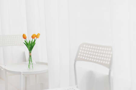 Tulips flower in a vase are placed on a table in a white room background with copy space.の写真素材