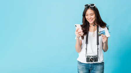 Asian pretty woman tourist preparing for travel and shopping online with smartphone and credit card...