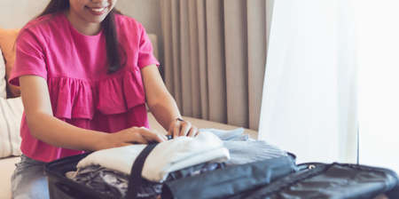 Asian woman packing bag for a trip at weekend vacation.Concept of happy travel lifestyle.
