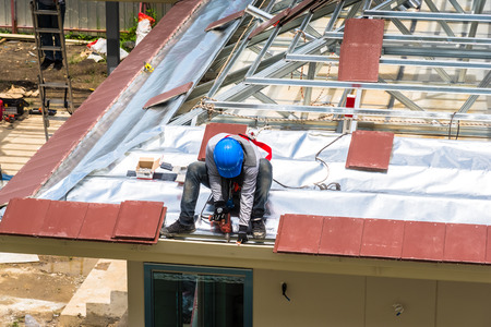 Workers are drilling roof tiles with a drill.