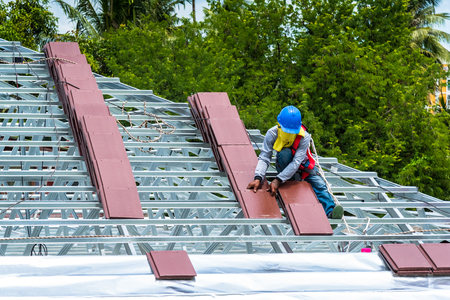 Workers are tiling new roof tiles.の写真素材
