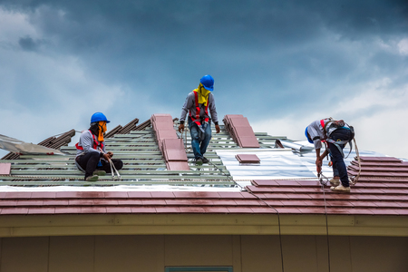 Workers are tiling new roof tiles.の写真素材