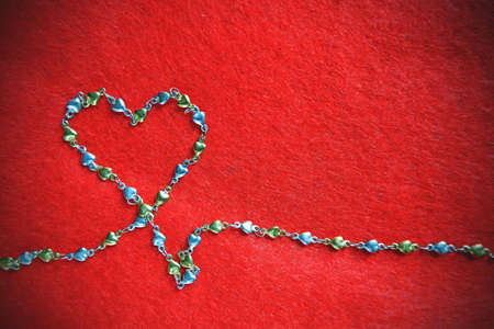 Heart shape from necklace on red background