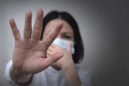 A woman with a mask has her hand up, forbid persons without a mask from approaching. To protect her...