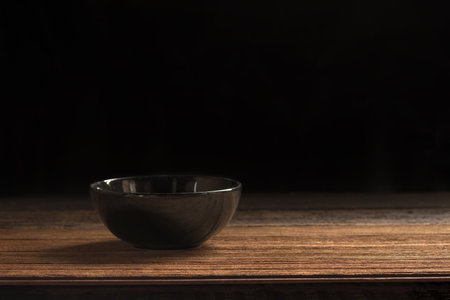 Ceramic black bowl on wooden board and black backdrop for presentation menu and montage food style.の写真素材