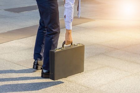 Young business man standing with his back carrying a briefcase city background, Start and forward Concept.の写真素材