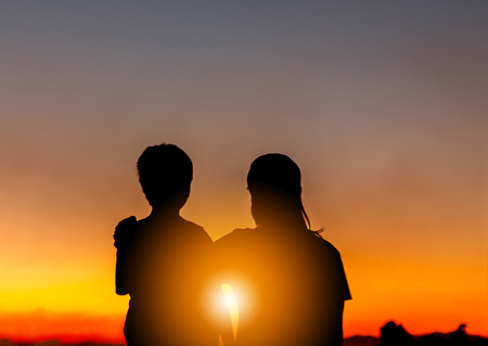 Silhouette of Mother and Son Watched Together at Sunset Evening Sky Background, Life and Happiness family Concept.の写真素材