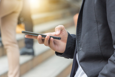 Close up of young business man using mobile smartphone blurry background.