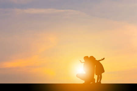 Silhouettes of Happy father and daughter playing at sunset evening sky background.の写真素材
