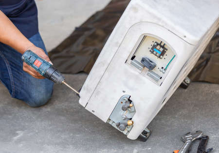 Selective focus Air Conditioning Repair, technician man hands using a screwdriver fixing modern air conditioning systemの写真素材