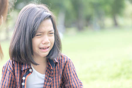 Mother looking at crying daughter, girl crying with tears in parkの写真素材
