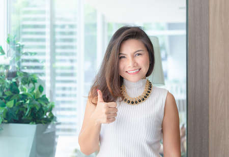 Happy successful confident smart young asian business woman smiling and showing thumbs up.の写真素材