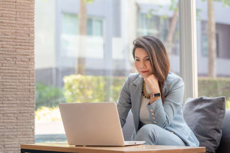 Beautiful Asian business woman working with computer laptop and thinking to get ideas, Business Startup Conceptの写真素材