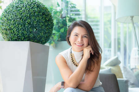 Happy successful confident smart young asian business woman sitting relax and smiling in office.の写真素材