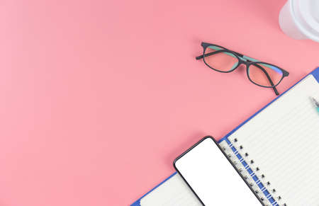 Top view with copy space of smartphone book glasses and pen overhead on pink pastel background, Flat lay and Mock up conceptの写真素材