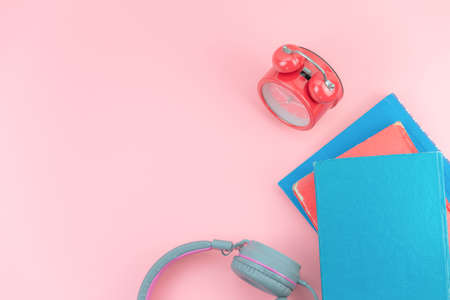 Top view with copy space of books, red clock and headphones overhead on pink pastel background, Flat lay and relaxing conceptの写真素材