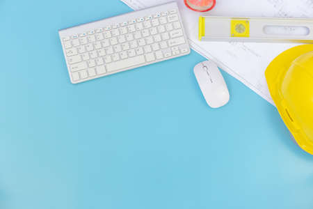 Top view with copy space of Engineering tools and computer keyboard, blueprints, helmet, measuring tape overhead on blue pastel background, Flat lay conceptの写真素材