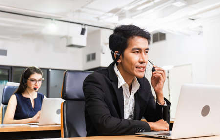 Young telephone operator with headset, Customer service executive team working at officeの写真素材