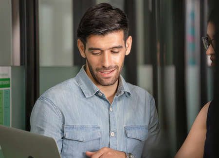 Man holding laptop and walking discusses work with female team, Young business team of coworkers meeting in creative officeの写真素材