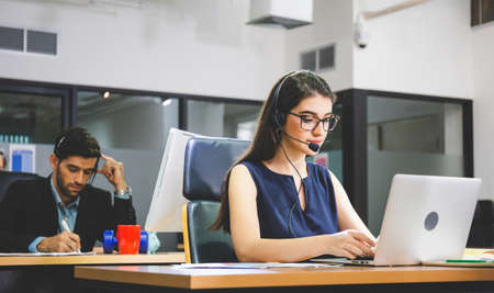Young woman telephone operator with headset working on laptop computer, Customer service executive working at officeの写真素材