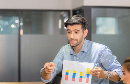 Young business team of coworkers meeting in creative office, businessman holding paper and sitting on table, Teamwork conceptの写真素材