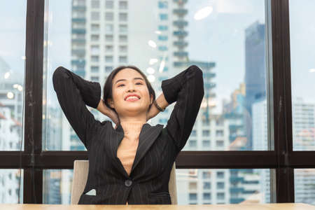 Young businesswoman relaxing at her desk in modern officeの写真素材
