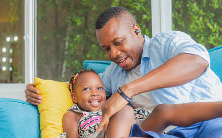 Cheerful african american father and daughter playing in living room, Happiness family conceptの写真素材