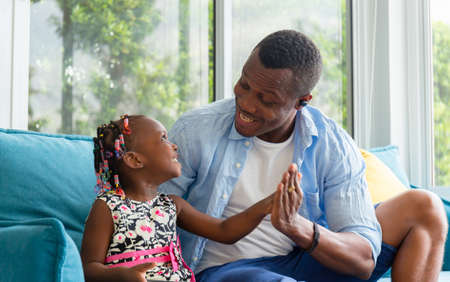 Cheerful african american father and daughter playing in living room