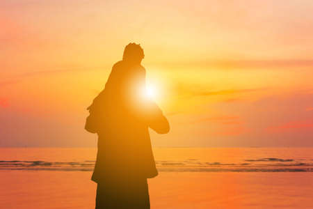 Silhouette of father carrying daughter on shoulders sunset sky at beachの写真素材