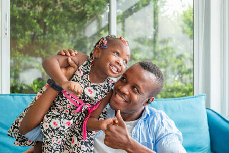 Cheerful african american father and daughter playing in living room, Happiness family conceptの写真素材