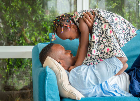 Cheerful african american father and daughter playing in living room, Happiness family conceptsの写真素材