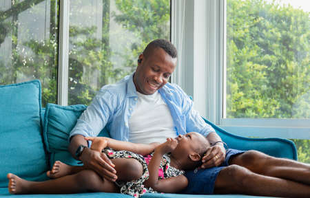 Cheerful african american father and daughter playing in living room, Happiness family conceptの写真素材