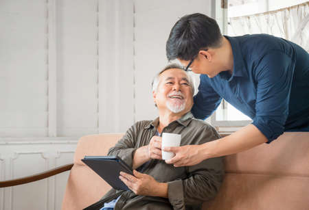 Cheerful senior asian father and middle aged son in living room, Happiness Asian family conceptsの写真素材
