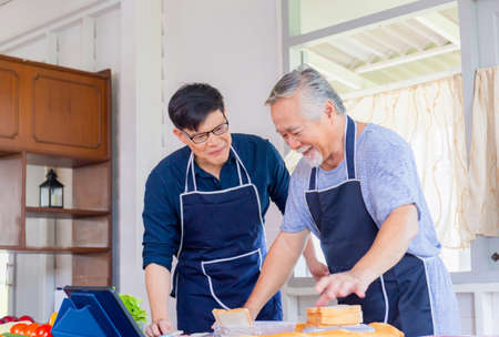 Cheerful senior asian father and middle aged son cooking together at kitchen, Happiness asian family conceptsの写真素材