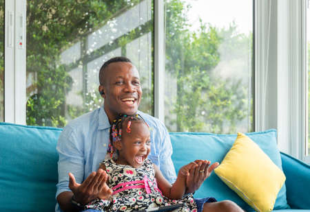 Cheerful african american father and daughter playing in living room, Happiness family conceptsの写真素材