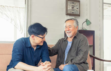 Cheerful senior asian father and middle aged son in living room, Happiness Asian family conceptsの写真素材