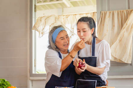 Senior asian mother and middle aged daughter cooking together at kitchen