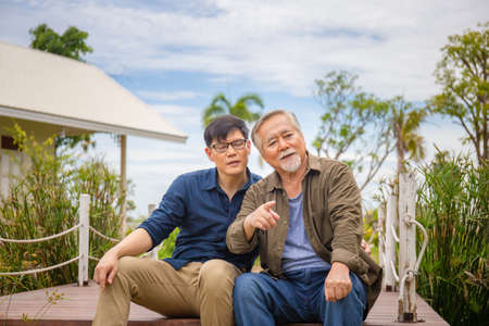 Senior asian father and middle aged son sitting relax together outdoors, Happiness Asian family conceptsの写真素材