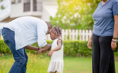 Happy father mother and daughter playing together outdoor, Cheerful african american family enjoying in the park, Happiness family conceptsの写真素材