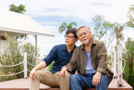 Senior asian father and middle aged son sitting relax together outdoors, Happiness Asian family conceptsの写真素材