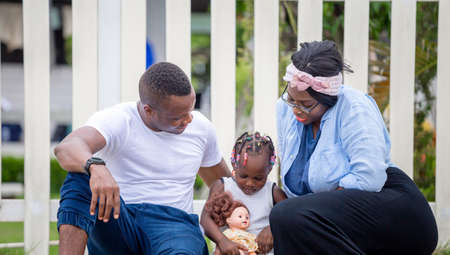 Happy father mother and daughter playing together outdoor, Cheerful african american family enjoying in the park, Happiness family conceptsの写真素材
