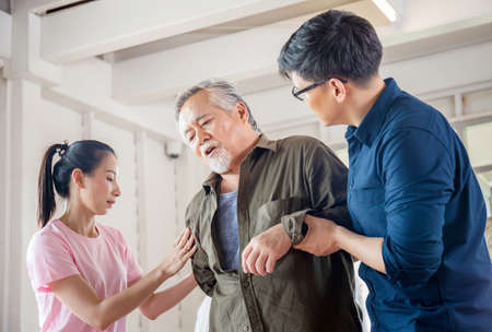 Son and daughter help support a senior father have a backache, Back pain in elderly adults, Asian family conceptsの写真素材