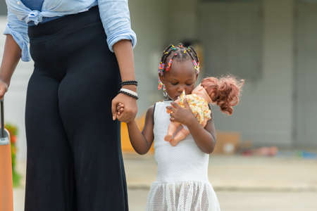 African american mother holding hand of her daughter, Sadly little girl holding and embracing her dollの写真素材