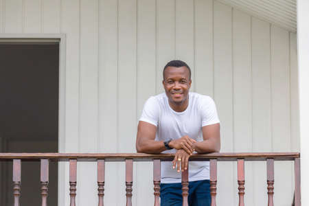 Cheerful african american man at wooden balcony and looking at cameraの写真素材