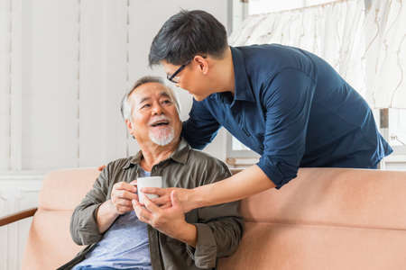 Cheerful senior asian father and middle aged son in living room, Happiness Asian family conceptsの写真素材